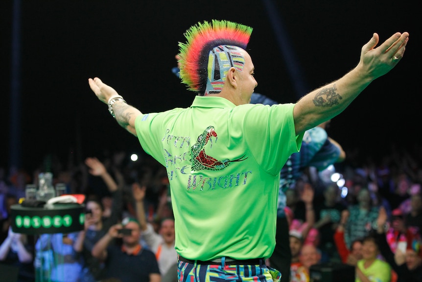 Peter Wright stands with his arms outstretched looking at the crowd with a pattern in his hair.