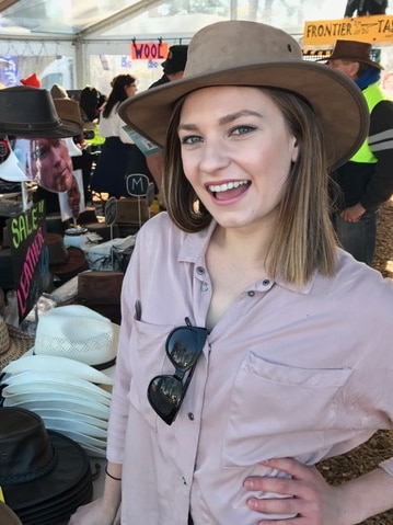 ABC reporter Carla Howarth tries on hats at Agfest 2017.