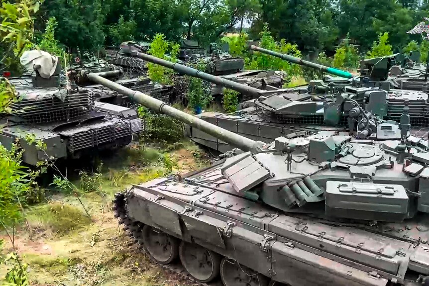 Large military tanks in a field.