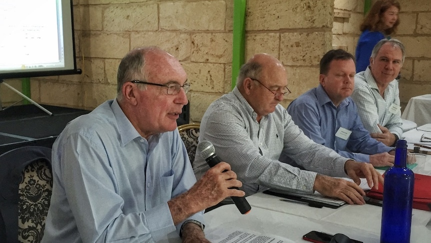 Four men sitting at a table at Kununurra with Warren Truss on left holding a microphone