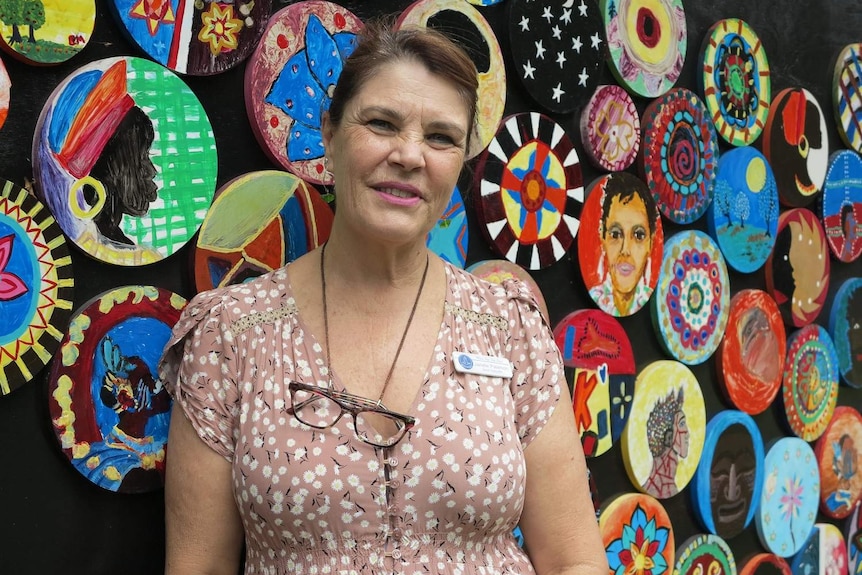 Janelle Patterson stands in front of coloured artwork on a wall at Milpera State High School.