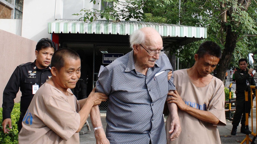 Detainees help Joseph Karl Kraus, a 90-year-old Australian man, as he leaves a court in Chiang Mai in Thailand.