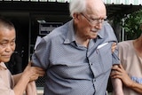 Detainees help Joseph Karl Kraus, a 90-year-old Australian man, as he leaves a court in Chiang Mai in Thailand.