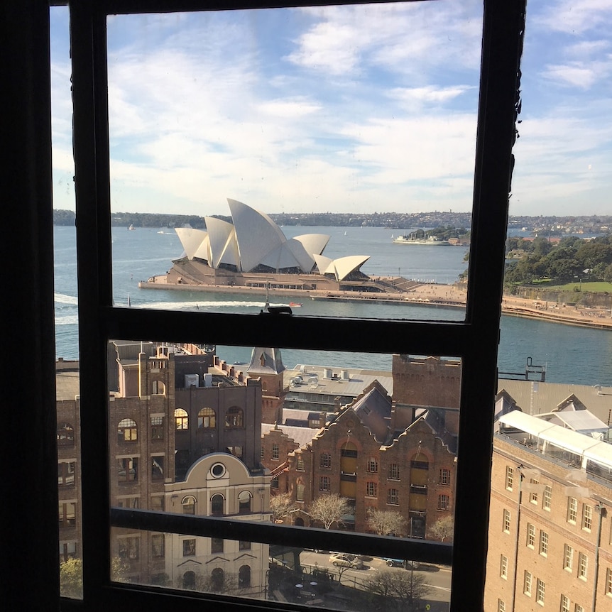 A sweeping view of Sydney's iconic Opera House, and harbour, as seen through a window.