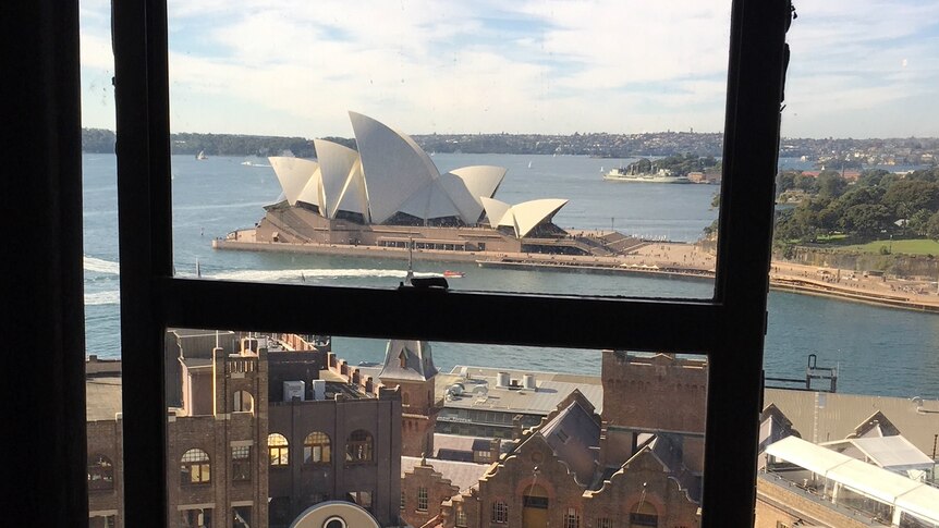 A sweeping view of Sydney's iconic Opera House, and harbour, as seen through a window.