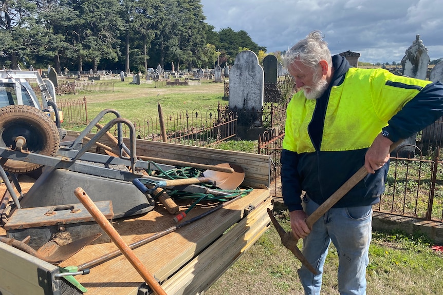 Man about to put a pick into the back of a ute. 