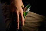 A man's hand holding a bottle of beer. 