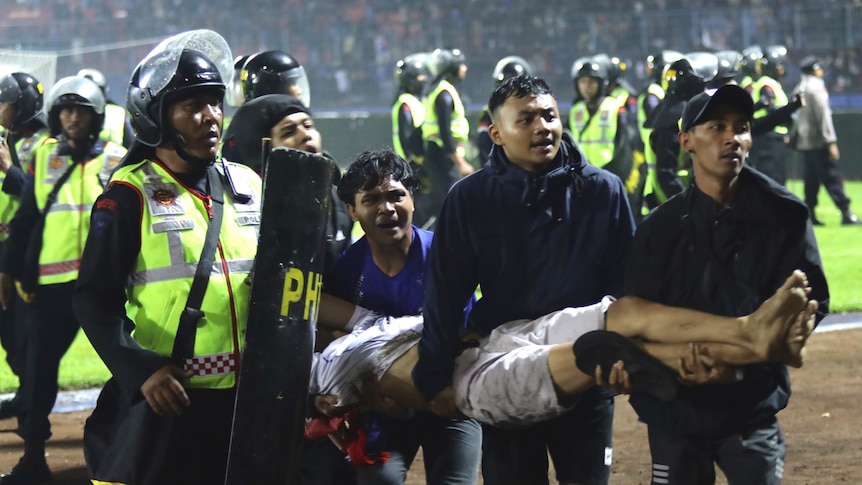 Police and upset fans carry an injured man off the field.
