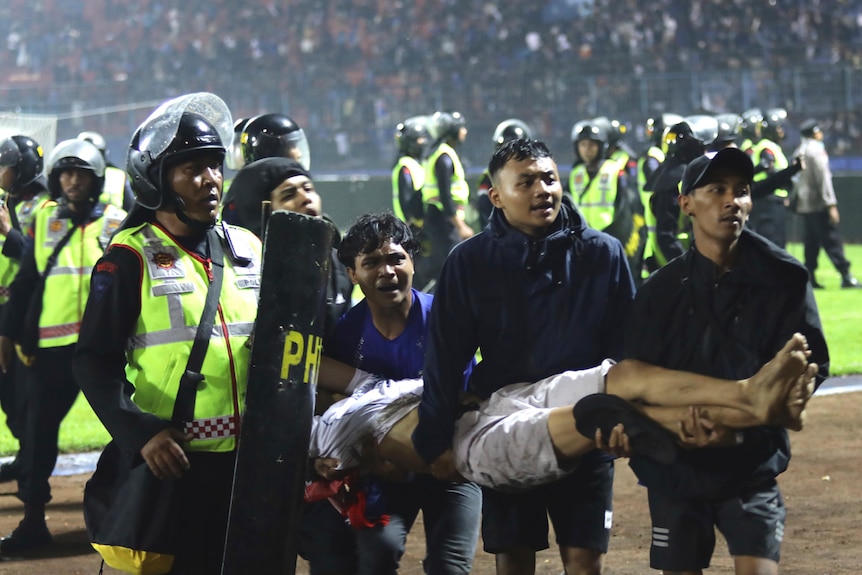 Police and upset fans carry an injured man off the field.