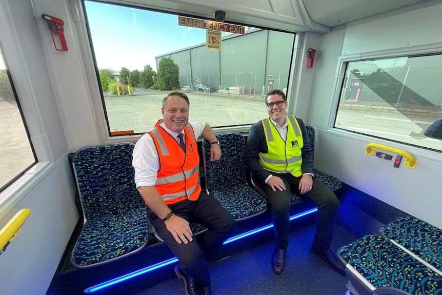 Two men in high-vis vests sitting in a fancy new bus