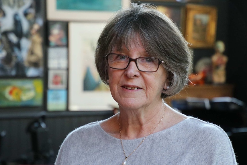 A head and shoulders shot of an older woman wearing spectacles and a grey jumper.