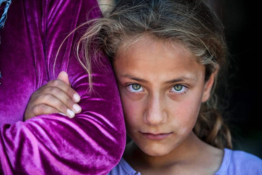 A tense smile from a traumatised Syrian girl in an Iraqi refugee camp.