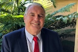 A middle-aged man wearing a suit, smiling