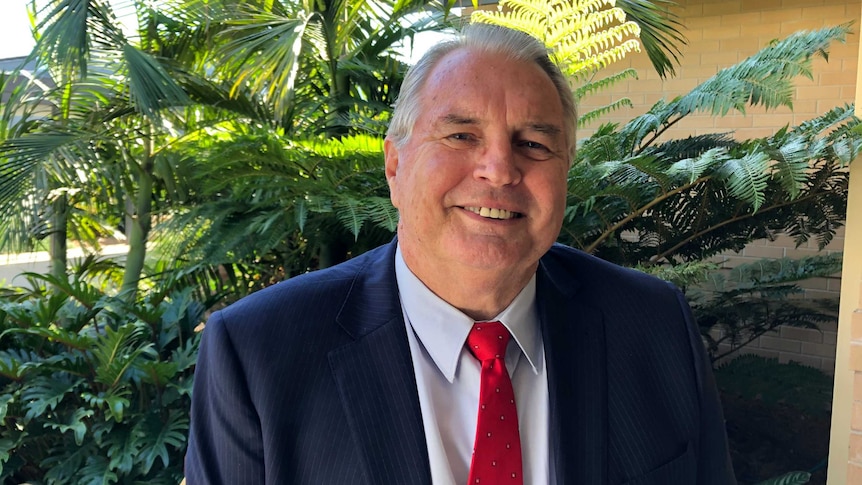 A middle-aged man wearing a suit, smiling