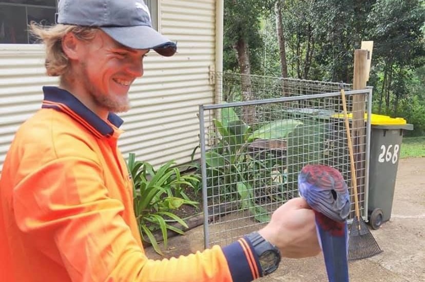 A young man smiling with a bird on his hand.