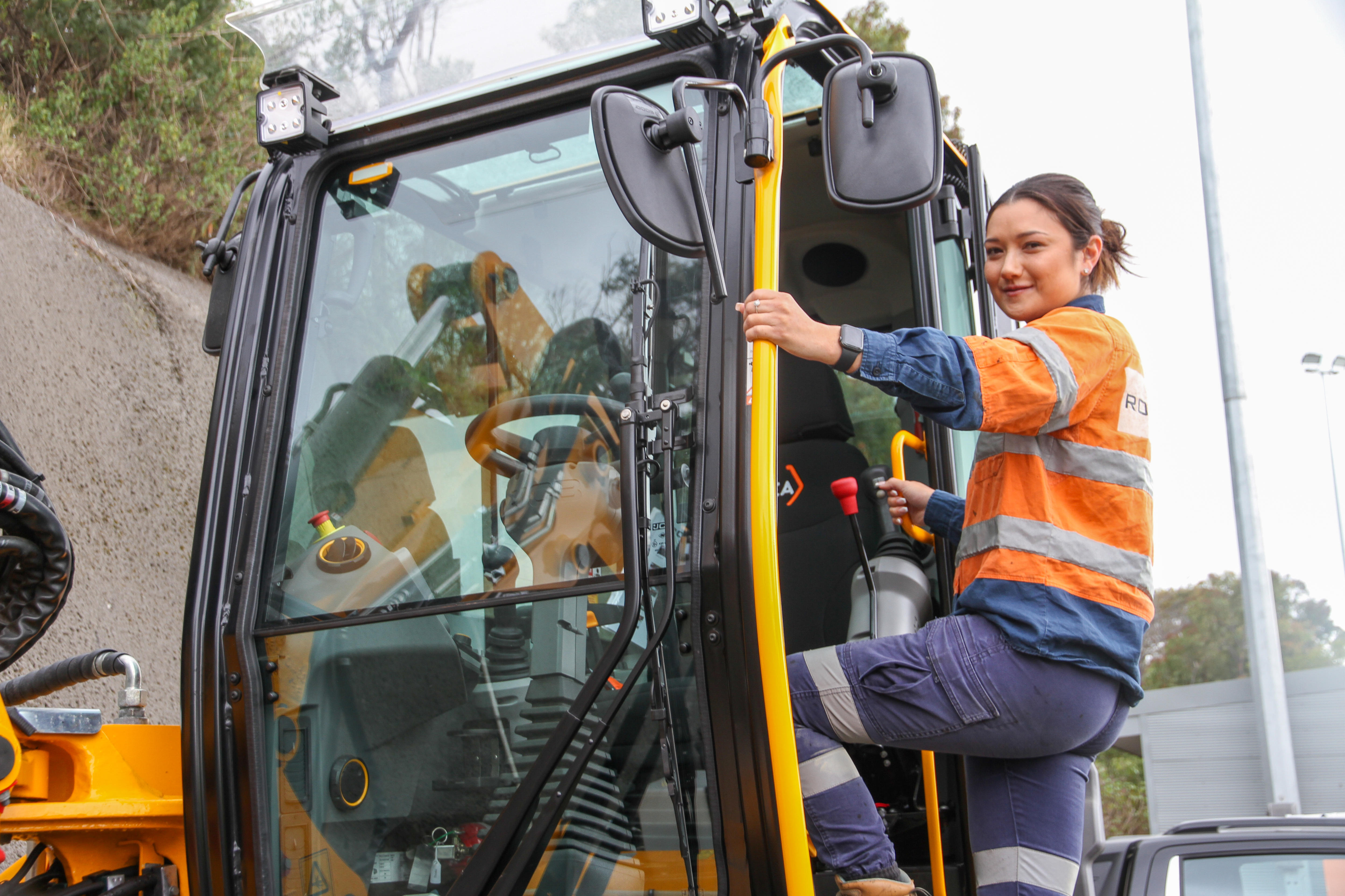 A young woman climbs into a cabin on a large machine