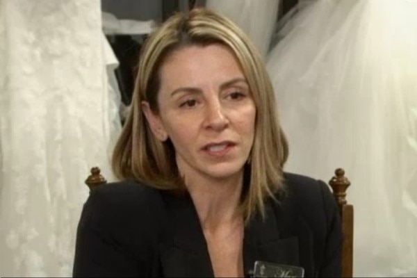 A woman seated in front of wedding dressses.