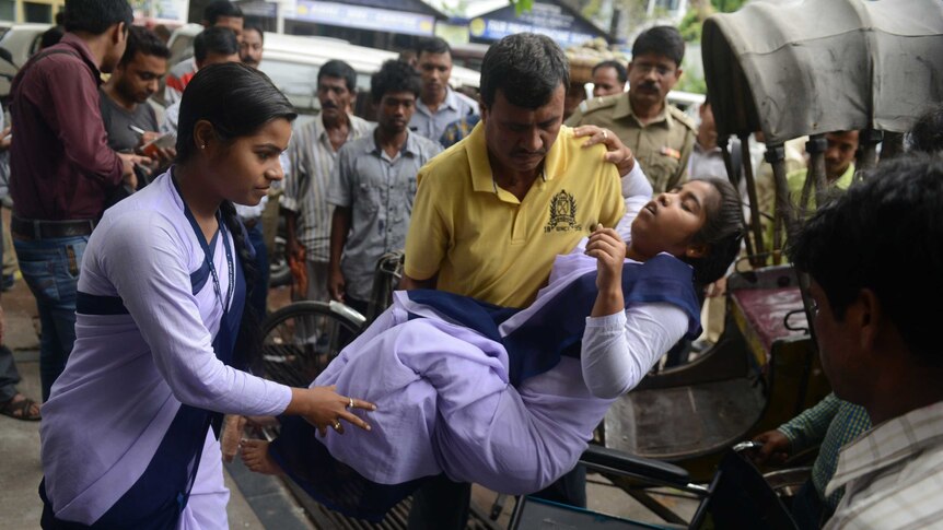 Indian hospital staff attend to a schoolgirl who fainted as a tremor struck