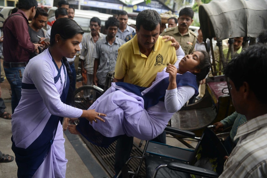 Indian hospital staff attend to a schoolgirl who fainted as a tremor struck