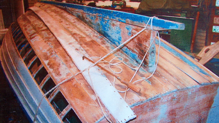 A wooden boat turned upside down in a workshop