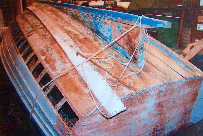 A wooden boat turned upside down in a workshop