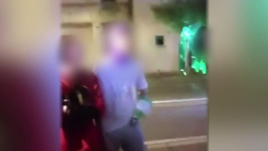 An image taken from a mobile phone video of two young men on a street with their faces blurred.