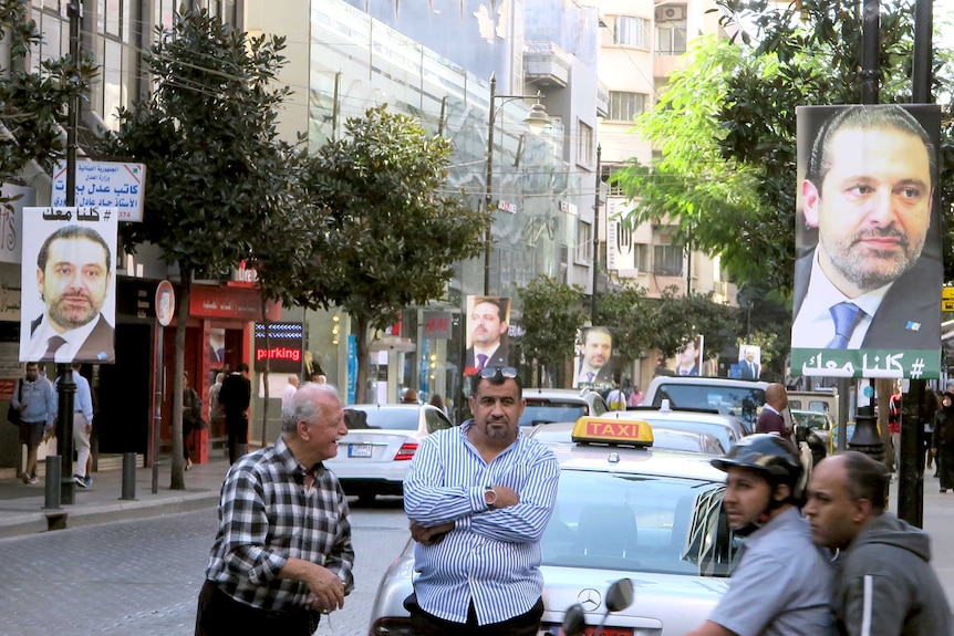 Taxi drivers standing in front of posters showing Lebanese Prime Minister Saad al-Hariri.