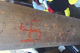 An orange swastika painted on a piece of wood