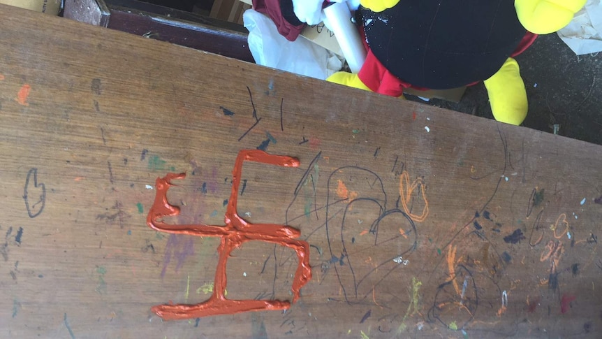 An orange swastika painted on a piece of wood