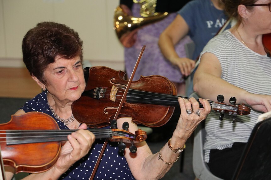 a woman playing the violin at an orchestra rehearsal