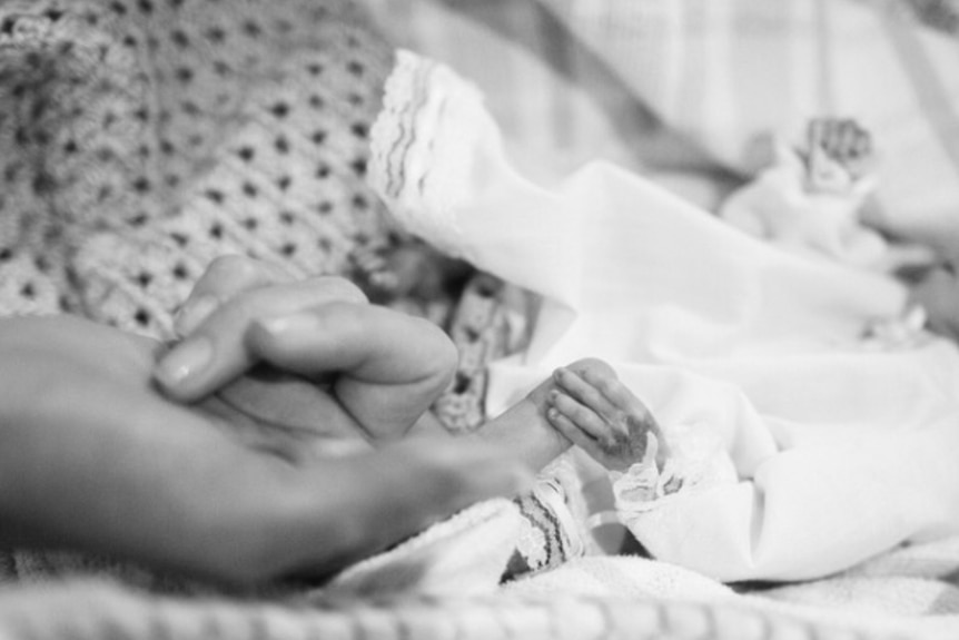Baby Zayden holding his mum's hand