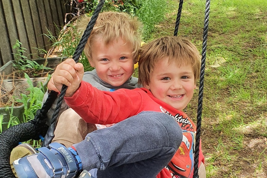 Two young boys in a tyre swing.