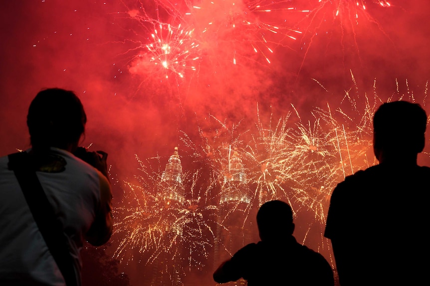 Bright red fireworks erupt over the skyline of Kuala Lumpur, with the Petronas Twin Towers in the background