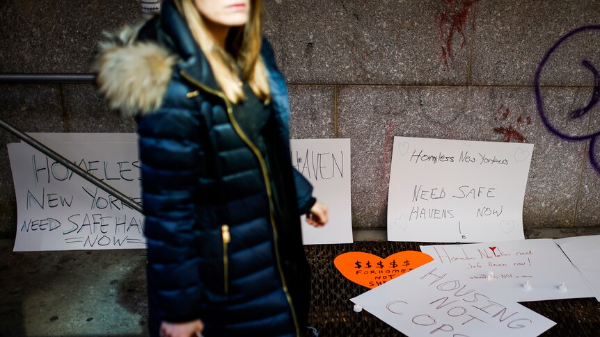 Woman walks by homeless memorial posters