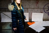 Woman walks by homeless memorial posters