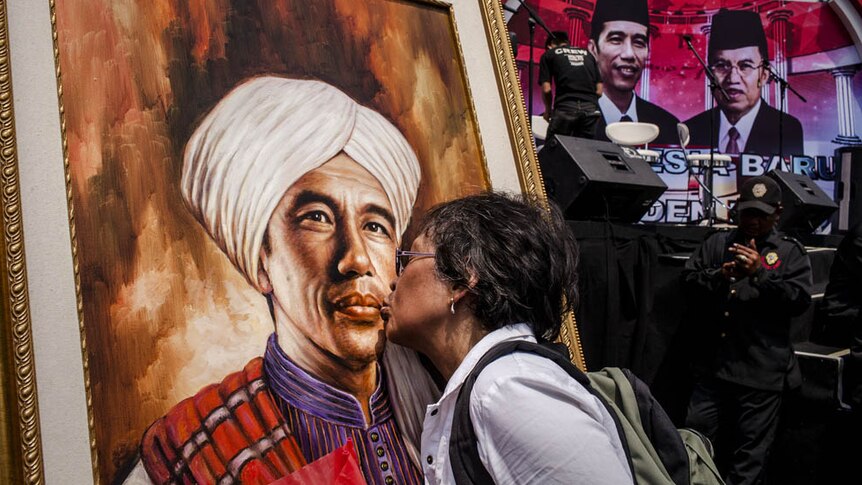 A woman kisses a picture of Indonesian President Joko Widodo