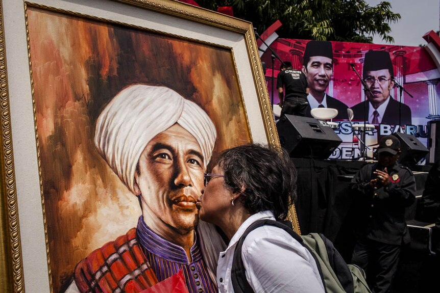 A woman kisses a picture of Indonesian President Joko Widodo