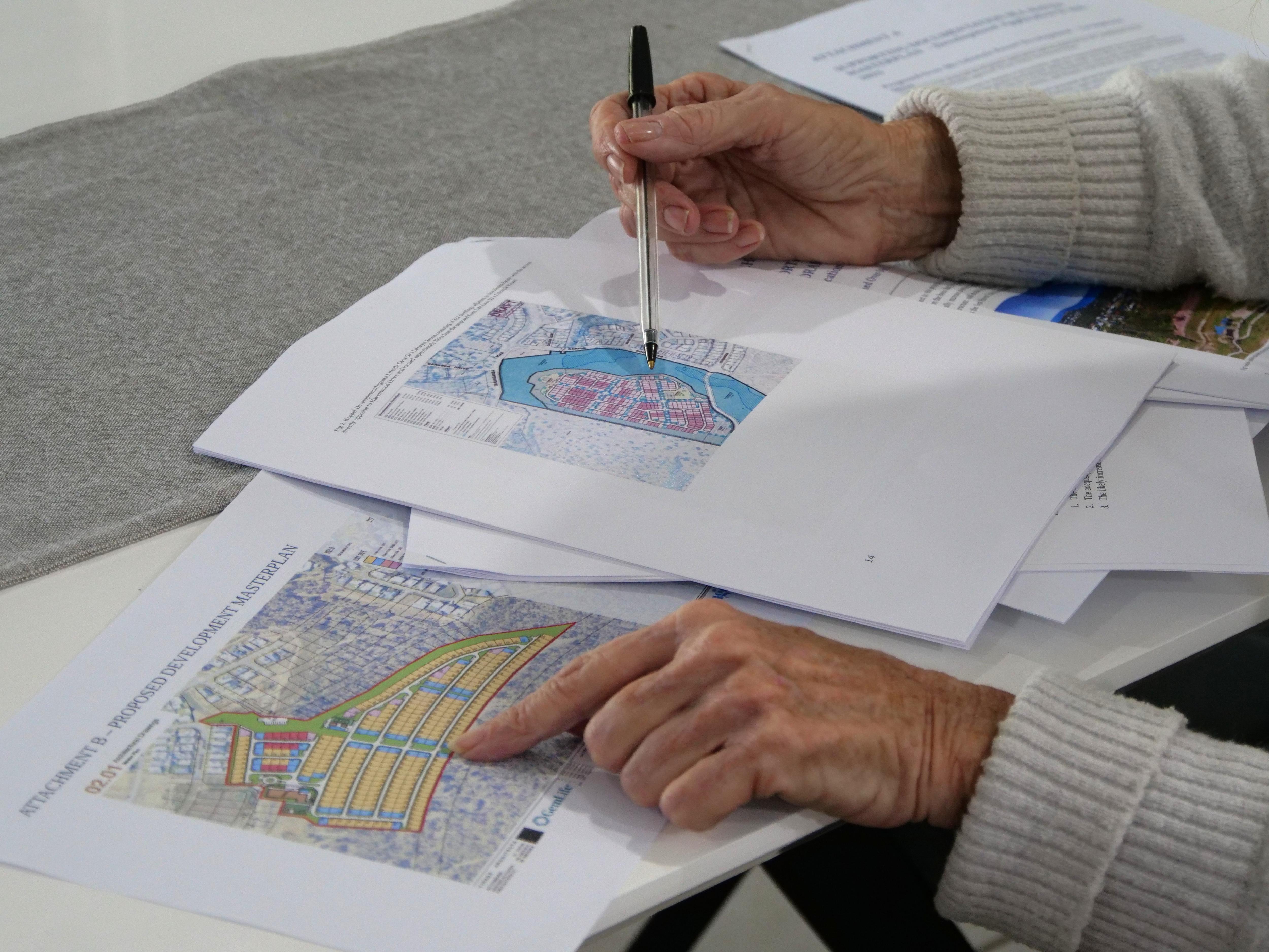 Hands pointing to maps on paperwork