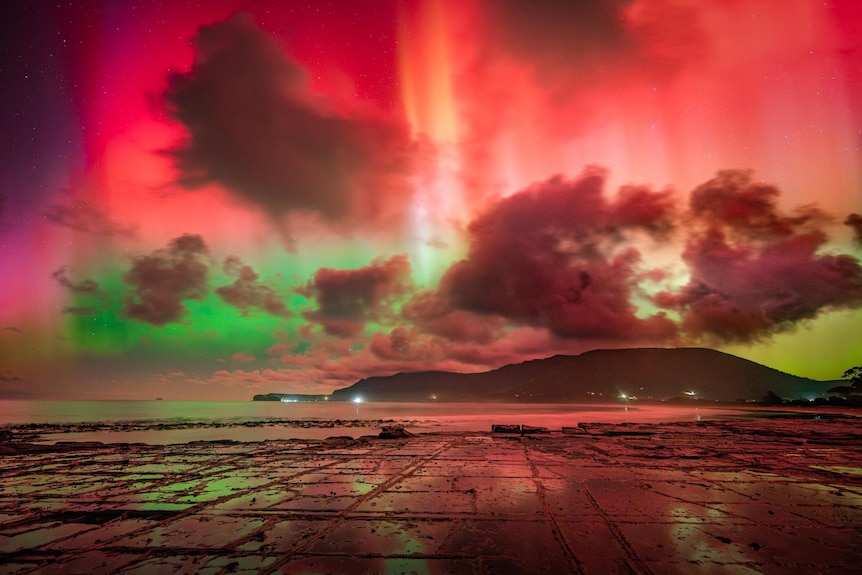 Green, red and yellow lights in the sky over a bay