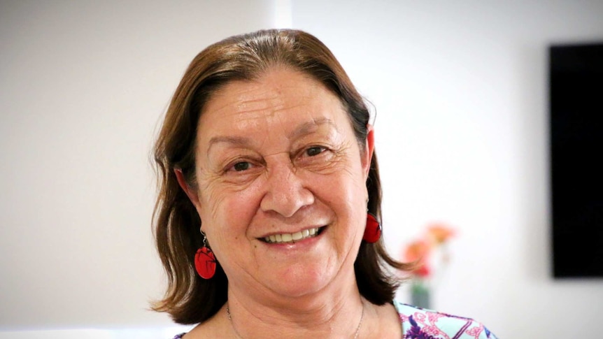 A woman wearing a floral dress smiles