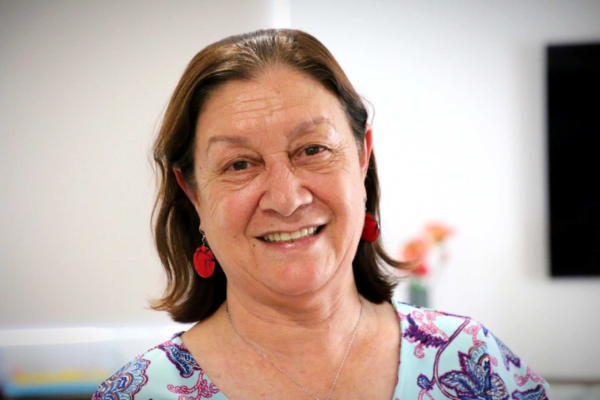 A woman wearing a floral dress smiles