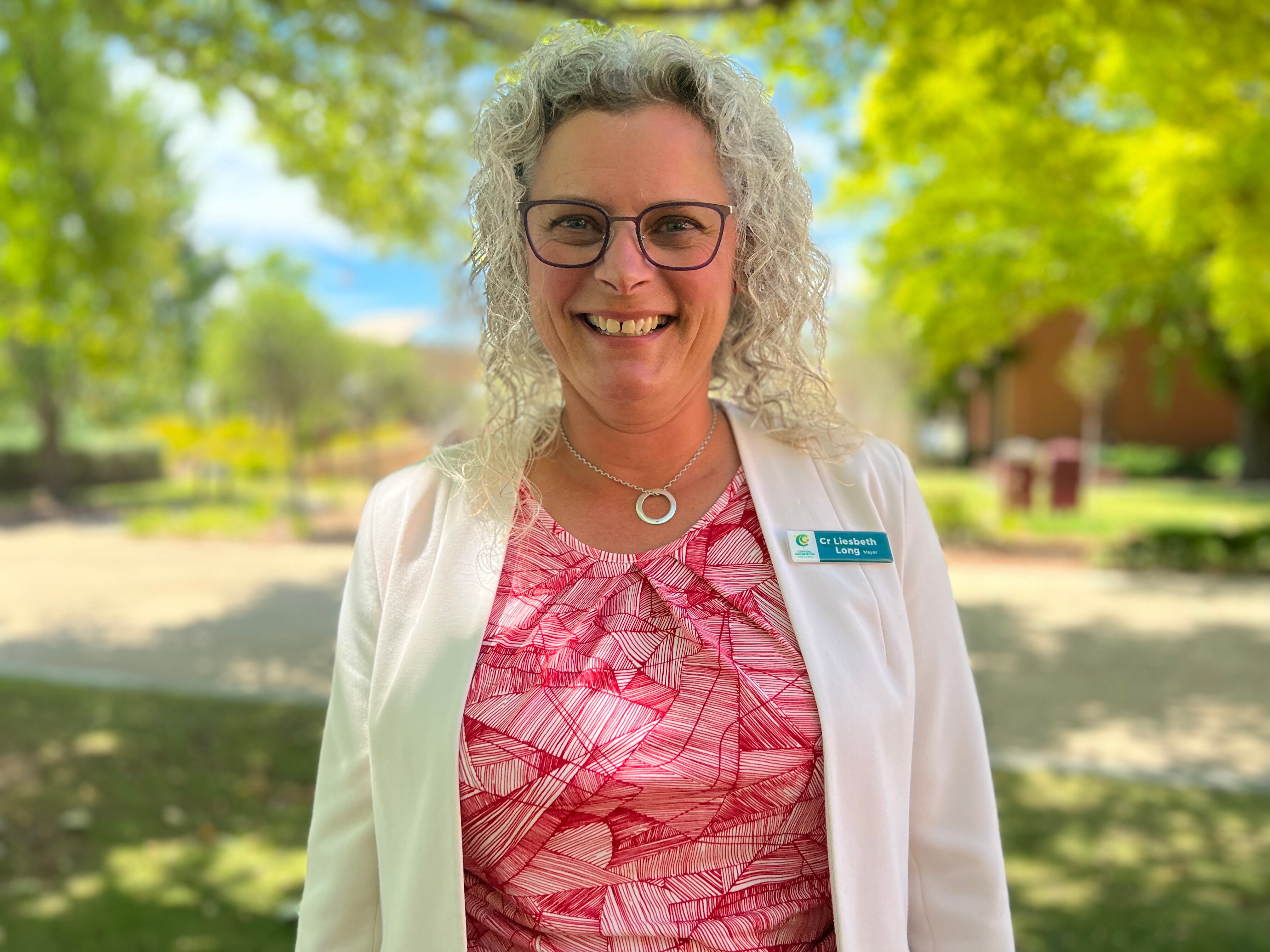 A lady with grey frizzy hair smiles at the camera
