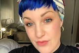 A woman with short, blue hair wearing a multicloured bandanna 