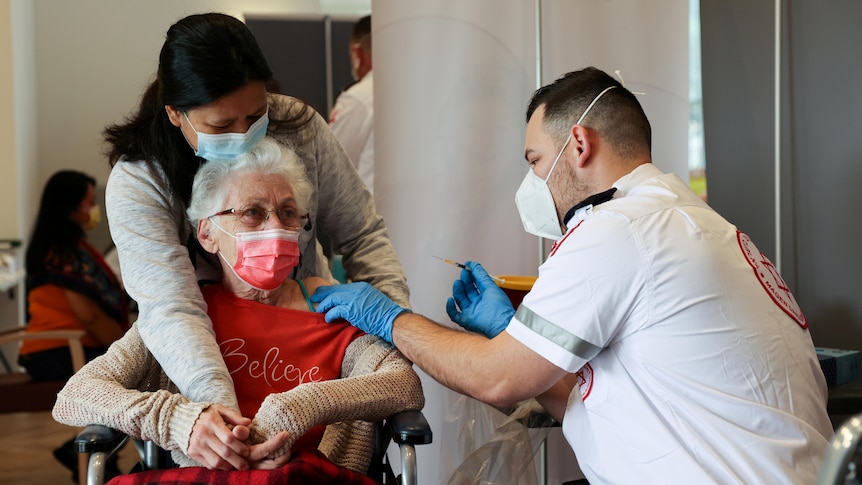 An elderly lady in a chair receives a vaccination against the coronavirus disease
