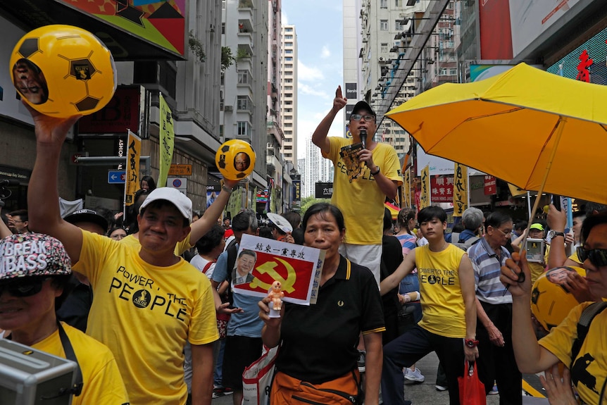 Protesters carrying yellow umbrellas, footballs and posters