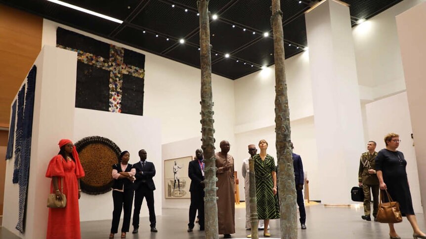 Visitors view various artworks in the shape of poles at varying heights at the Museum of Black Civilisation.