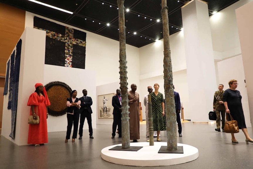 Visitors view various artworks in the shape of poles at varying heights at the Museum of Black Civilisation.