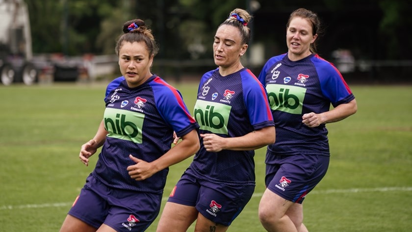 Three women running on a field.