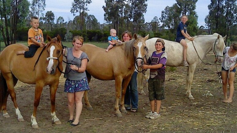 Queensland drover Jen McClelland standing with her family and their horses