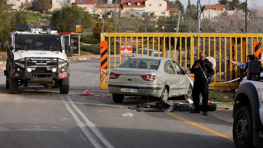 Israeli policemen stand at the scene of a stabbing attack north of Hebron